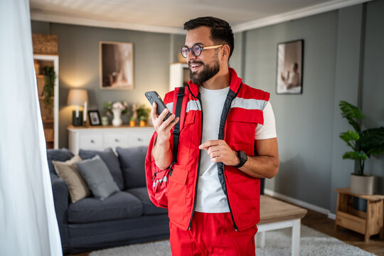 Paramedic man using smartphone wearing red uniform