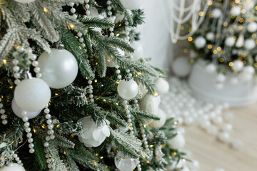 The artificial Christmas tree, made of environmentally friendly materials, is decorated with white plastic balls and pearl beads. Christmas tree in the interior of a residential building