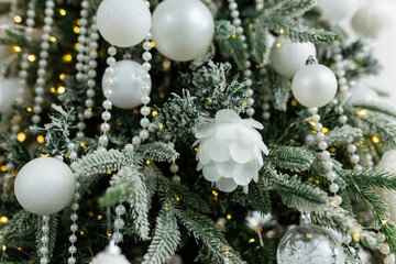 The artificial Christmas tree, made of environmentally friendly materials, is decorated with white plastic balls and pearl beads. Christmas tree in the interior of a residential building