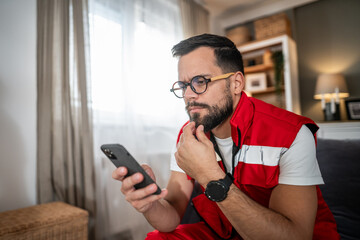 Paramedic man using smartphone at home