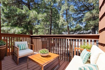 A balcony with a couch, chair, table, and trees behind it