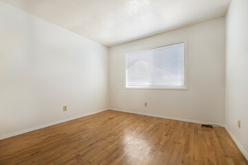An empty bedroom featuring hardwood floors and a wellplaced window