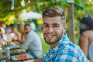 Young man smiling at a summer outdoor gathering with friends