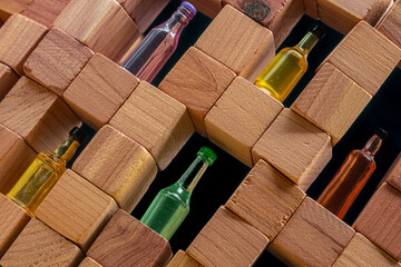 A wall made of wooden cubes with various miniature bottles of alcohol without labels on dark bacground