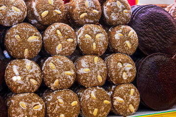 A closeup of stacked handmade german gingerbreads with almonds at a christmas market stall, showing texture, tradition, and holiday craftsmanship