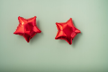 Red star-shaped balloons on a light green background for celebrations and parties