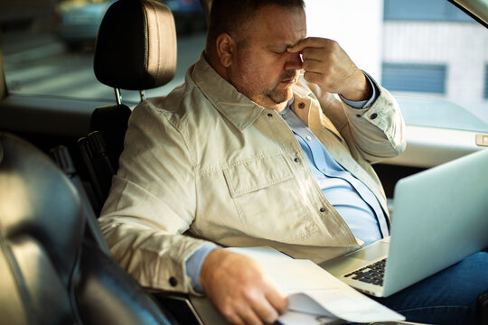 Adult man stressed while working on laptop in car