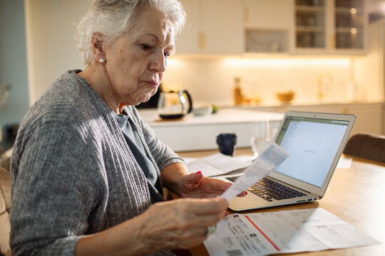 Senior woman concerned paying bills on laptop at home
