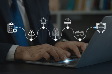 Workplace safety management concept. Typing on a laptop with safety icons; risk assessment, hazard alerts, personal protective equipment (PPE). Managing workplace safety protocols and compliance.