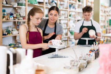 Woman master potter teaches teen girl how to draw and glaze pottery