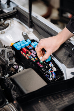 Mechanic replacing car fuse in engine bay fuse box, auto service maintenance close up