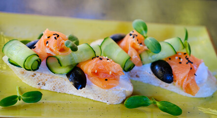 Sandwiches with salted salmon, cream cheese and cucumber on white plate, Top view. High quality photo
