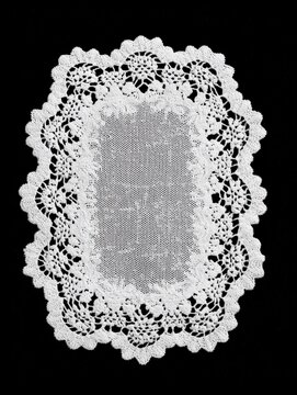 Rectangular white lace doily with scalloped border on black background