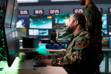Army operative analyzing surveillance data during international war. African american intelligence agent in base of operations completes mission during World War 3 geopolitical operation