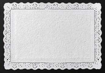 White lace edge rectangular paper doily on dark grey background