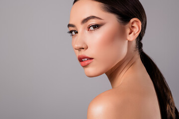 Fototapeta premium Portrait of a charming young woman with flawless makeup, showcasing a sleek hairstyle and radiant skin