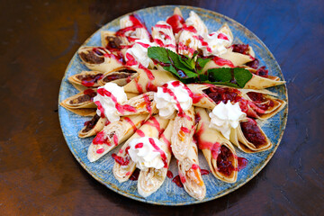 Crepes stuffed with chocolate spread and banana on white plate. Thin pancakes, blini. Sweet dessert. High quality photo