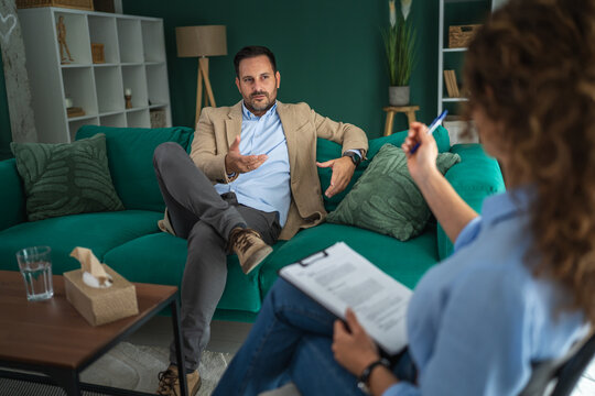 Male client talking during psychotherapy session with therapist
