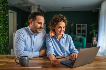 Happy couple online shopping using laptop and credit card