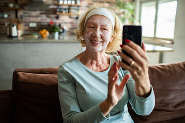 Senior woman smiling during video call with face mask at home