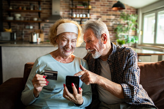 Senior couple laughing at home while shopping online