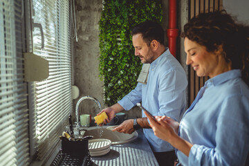Couple working together doing household chores in kitchen