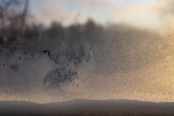 Frosted windowpane with blurred winter landscape background
