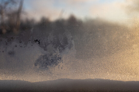 Frosted windowpane with blurred winter landscape background