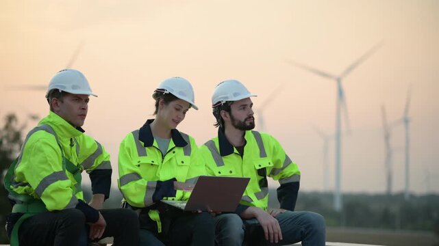 Team of engineers wearing safety helmets inspecting wind turbines at a wind farm. teamwork renewable energy, sustainable development, clean technology environmental engineering wind power generation.