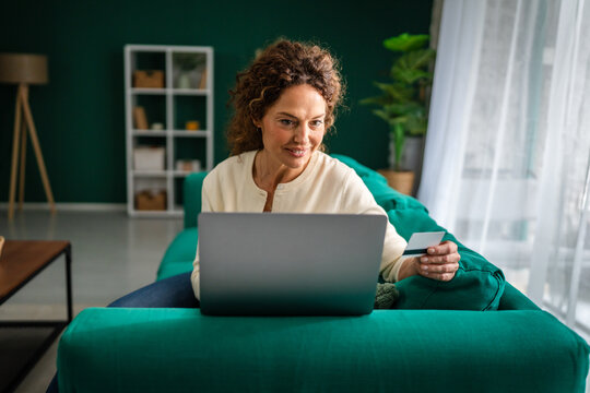 Woman shopping online with laptop and credit card on couch