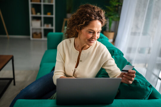 Woman shopping online with laptop and credit card on couch - Powered by Adobe