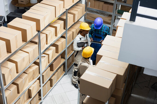 Multiethnic team examining cargo on racks for efficient distribution, managing the shipment process, inventory control, and packaging of goods for import export delivery service.