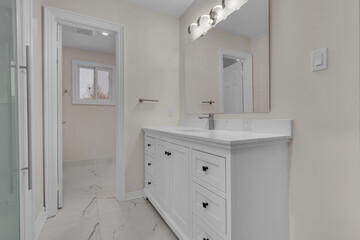 Bright, clean bathroom with white cabinets and marble flooring in modern style.