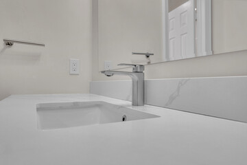 Sleek bathroom sink featuring modern faucet and bright white countertop design.