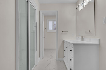 Clean bathroom interior with white cabinets, sliding glass shower doors and a mirror.
