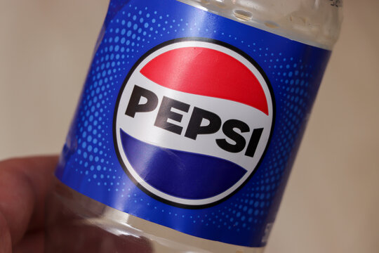 Warsaw, Poland - November 20, 2025: Close-up of a clear bottle featuring the iconic Pepsi logo against a vibrant blue background, showcasing brand identity and marketing appeal.