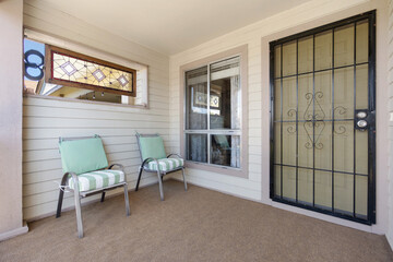 A charming porch featuring two comfortable chairs and a sliding glass door