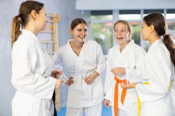 Group of young women are talking after successful and tedious aikido workout. Coach and students discuss speaking past former wrestling training