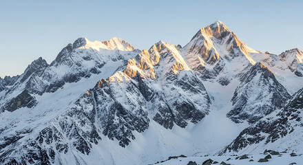 Majestic snow-capped mountains bathed in golden sunlight under a clear blue sky, showcasing rugged peaks and vast glaciers.