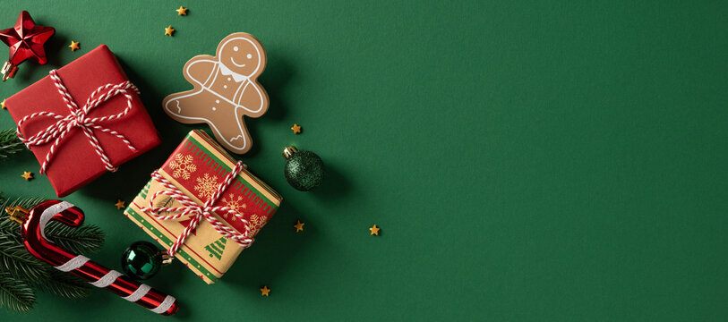 Festive holiday scene with red gifts, wrapped presents, candy cane, gingerbread figure, and green background. Pine cone, ornament, star, and lights evoke Christmas and New Year celebration