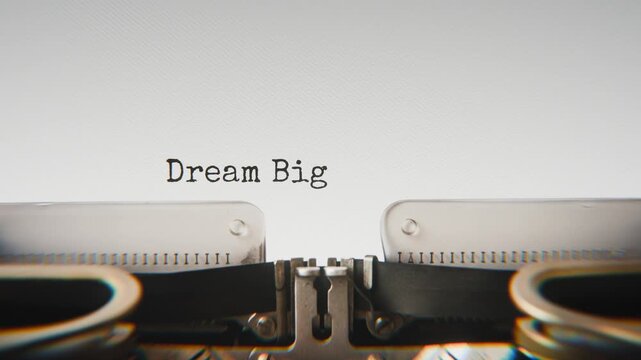 Old mechanical typewriter typing Dream Big Daily in a close-up view, with metal letters striking the white paper.