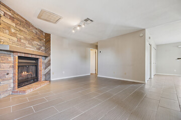 An empty living room featuring a fireplace complemented by a brick wall