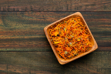 Calendula officinalis - Organic calendula petals in a square wooden bowl