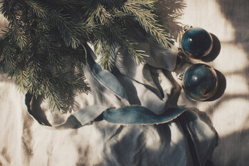 Christmas holiday flat lay with vintage decorations, pine branch, blue velvet ribbon, and glass ornament on linen fabric, creating nostalgic and cozy festive atmosphere