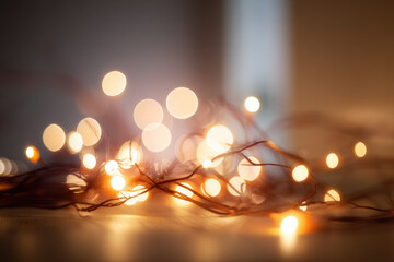 Soft glowing orbs and blurred garland lights create dreamy festive atmosphere with warm tones, perfect for holiday decoration or cozy indoor ambiance