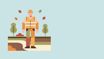 Worker in safety gear standing in an autumnal park setting