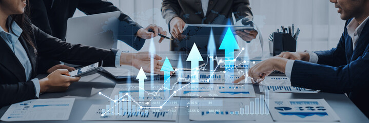 A diverse group of professionals collaborate in a business meeting, analyzing data through digital interfaces and graphs to drive informed strategic decisions and insights. Scalp