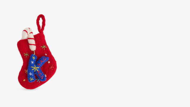 Colorful holiday stocking decorated with stars and candy cane design hanging on a light background.