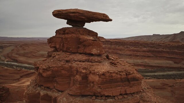 Aerial fly by past Hat Rock near Mexican Hat, UT with overcast skies