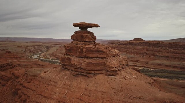 Aerial fly by past Hat Rock near Mexican Hat, UT with overcast skies